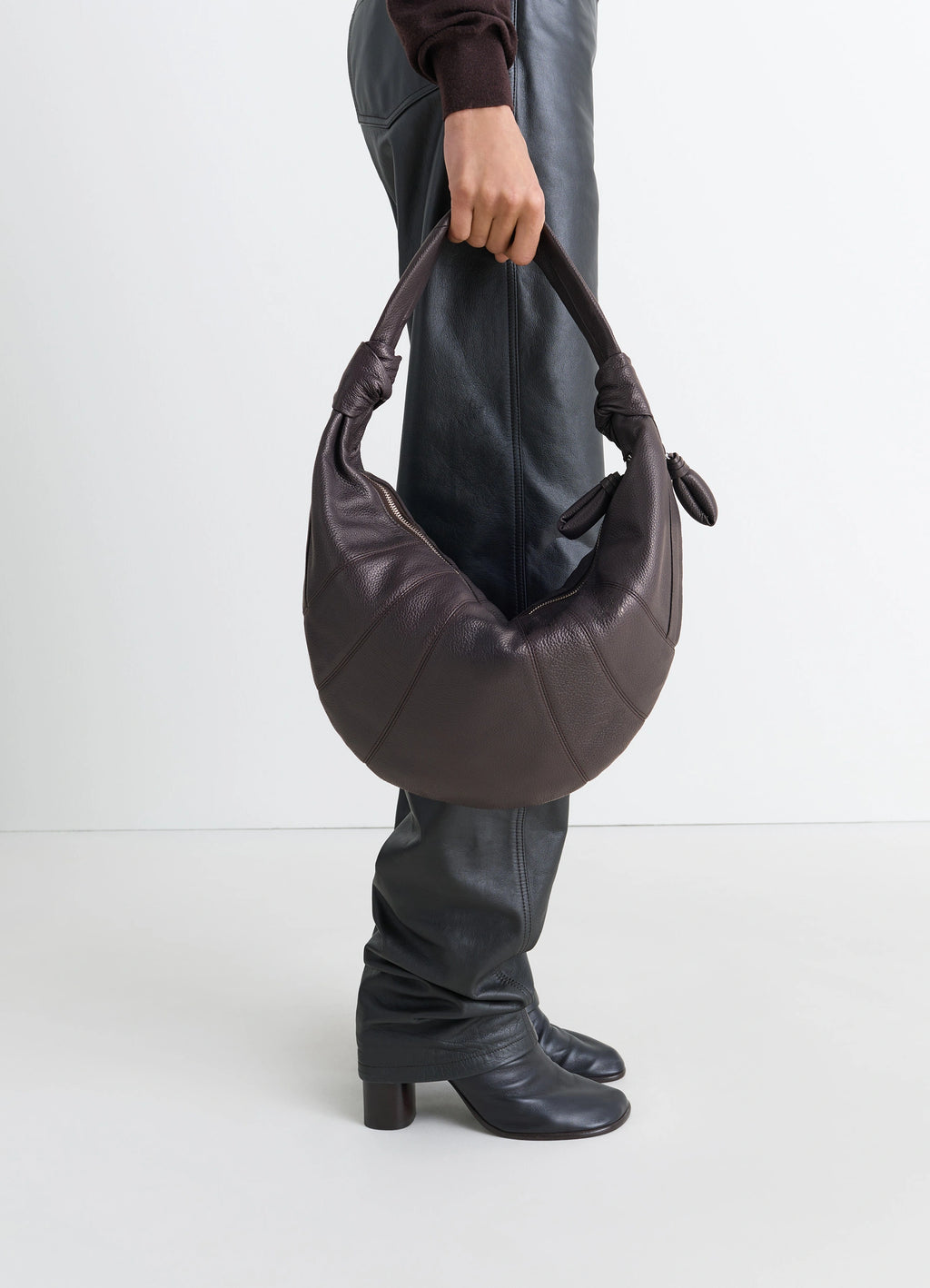 Fortune croissant bag in grained leather, model shot, held by model soft crescent shape