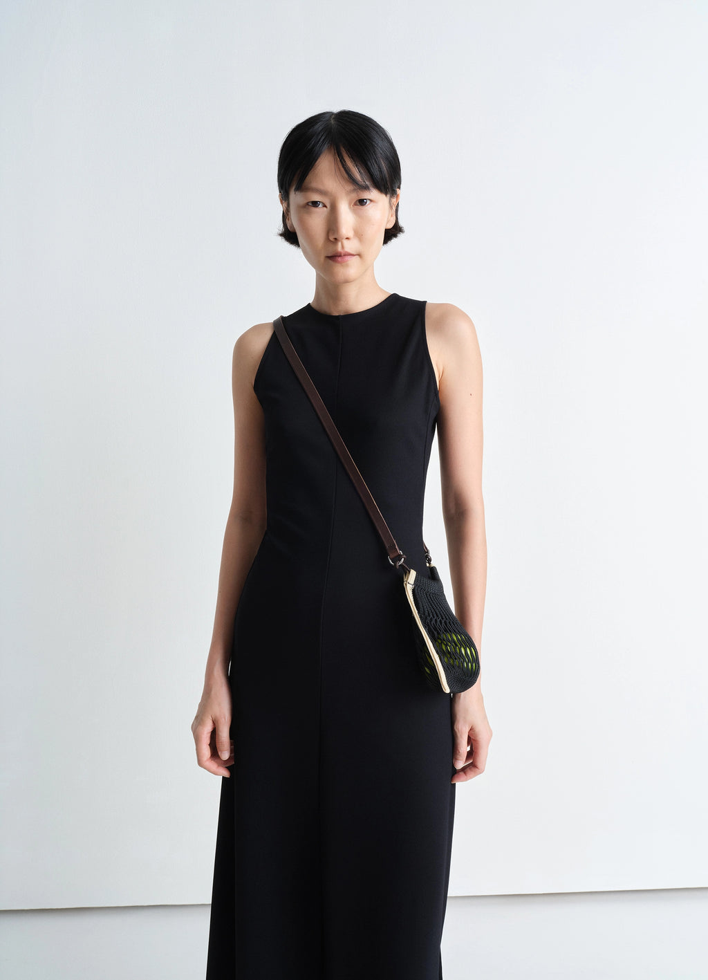 Mini crossbody filt net bag in dark chocolate leather, nylon, model shot, front view crossbody worn over black dress