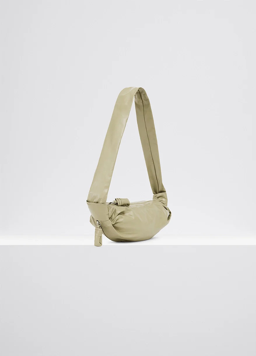 Small soft croissant in lightweight shiny leather, product shot, dynamic angled shot long shoulder strap