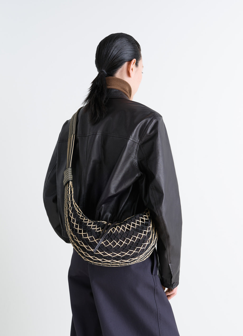 Croissant filt bag in nylon net black, model shot, over-the-shoulder view woven grid pattern