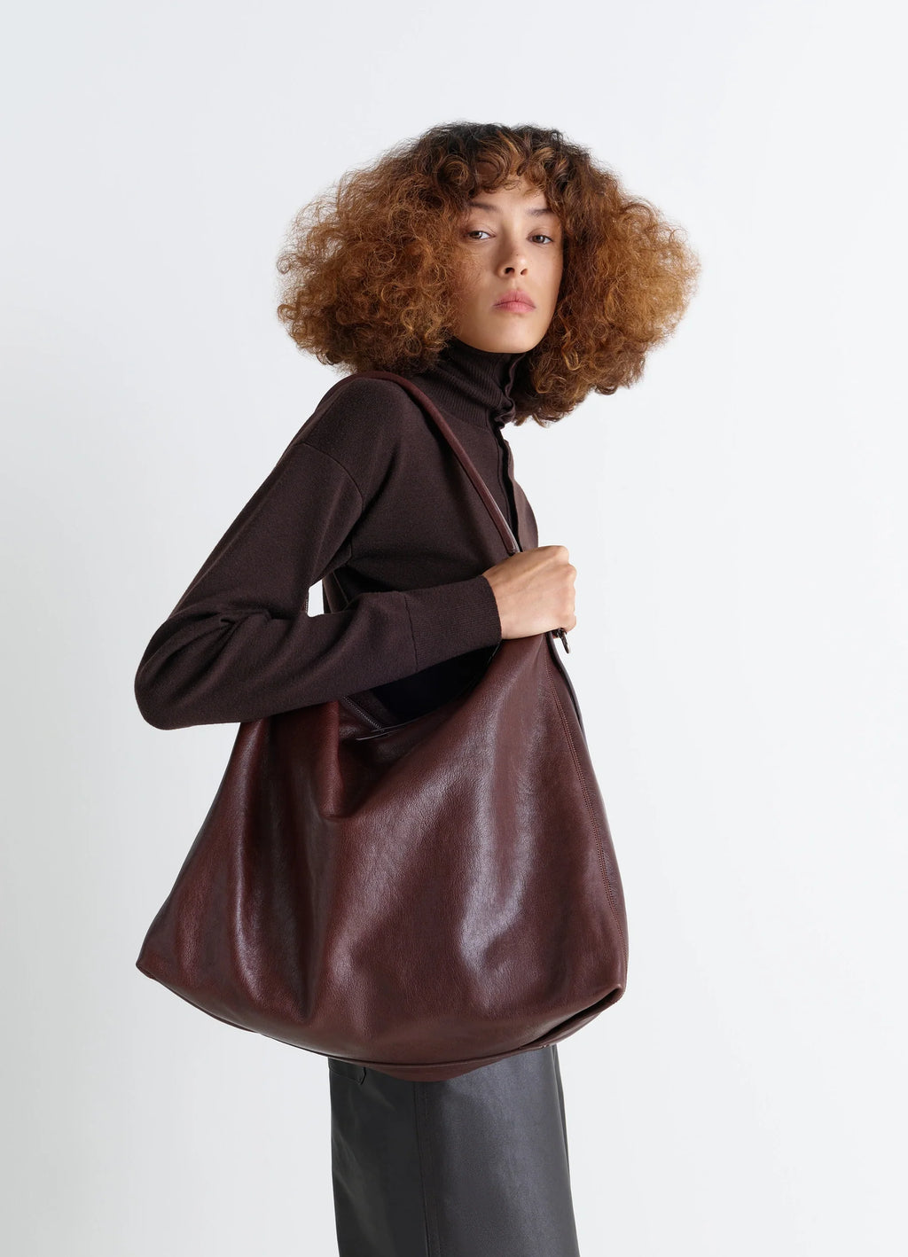 Belted hobo bag in glazed paper leather, model shot, side view minimalist utilitarian design