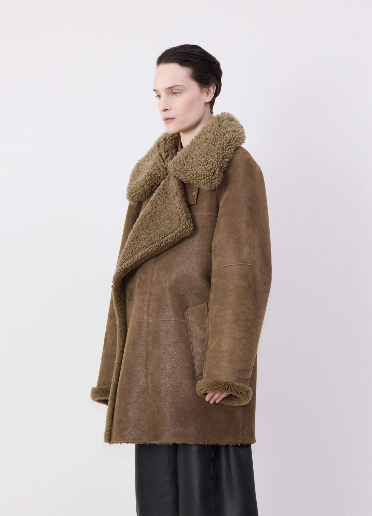 Lemaire Asymmetrical Shearling Coat in Curly lamb shearling with leather, model shot, Three-quarter side  Boxy oversized with