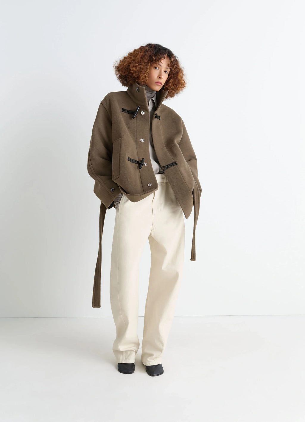 Lemaire short duffle coat in olive double-faced wool, model shot, side angle view shiny piping details