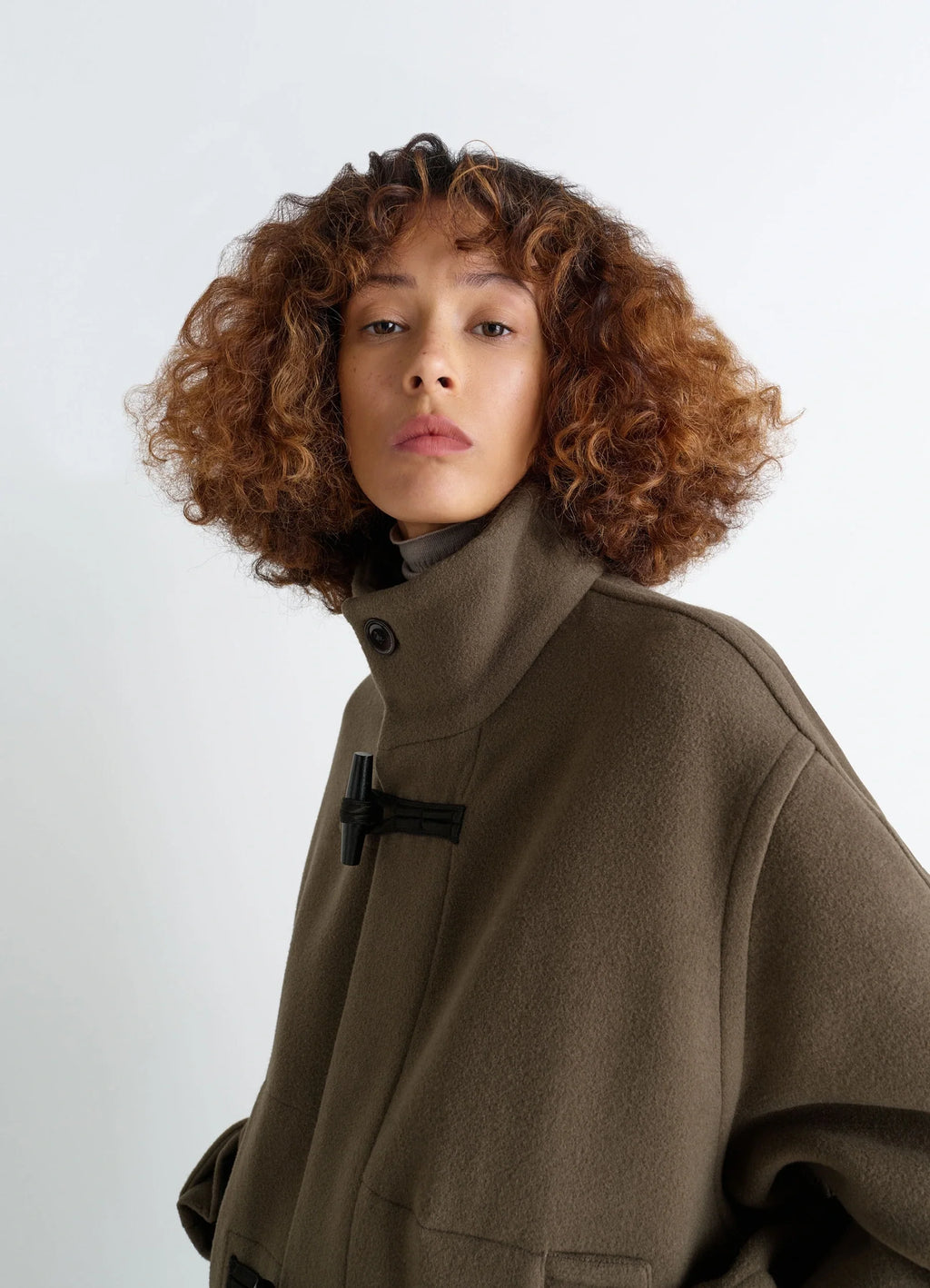 Lemaire short duffle coat in olive double-faced wool, model shot, three-quarter view buttoned high neck