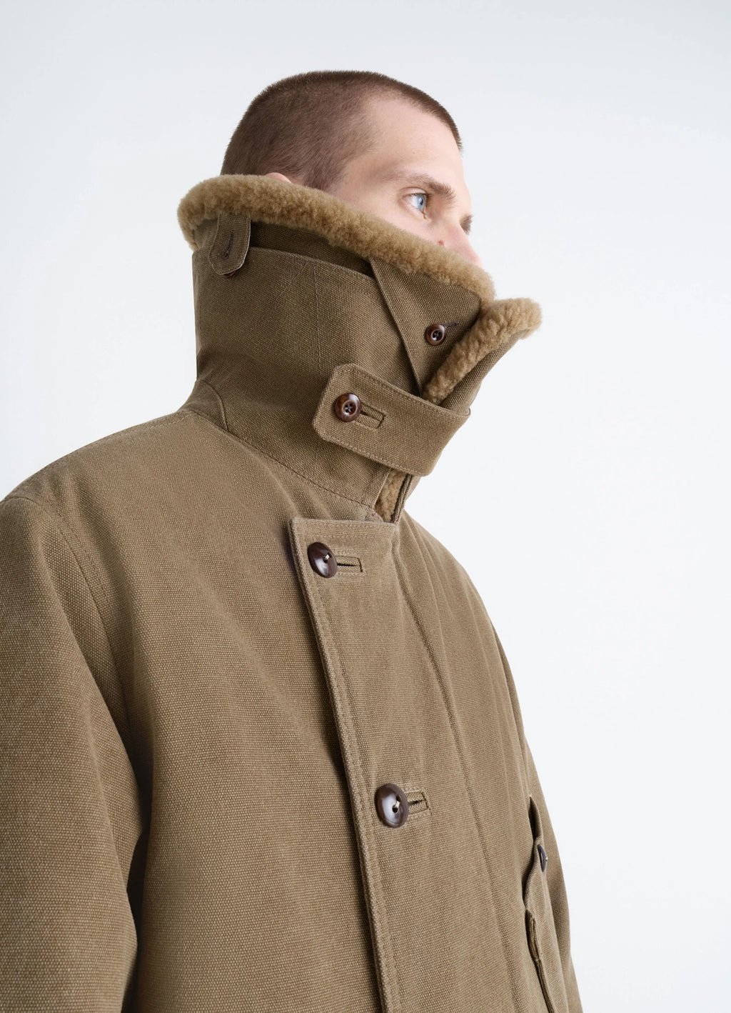 Shearling winter parka in brown cotton canvas, model shot, side detail view high collar fastened