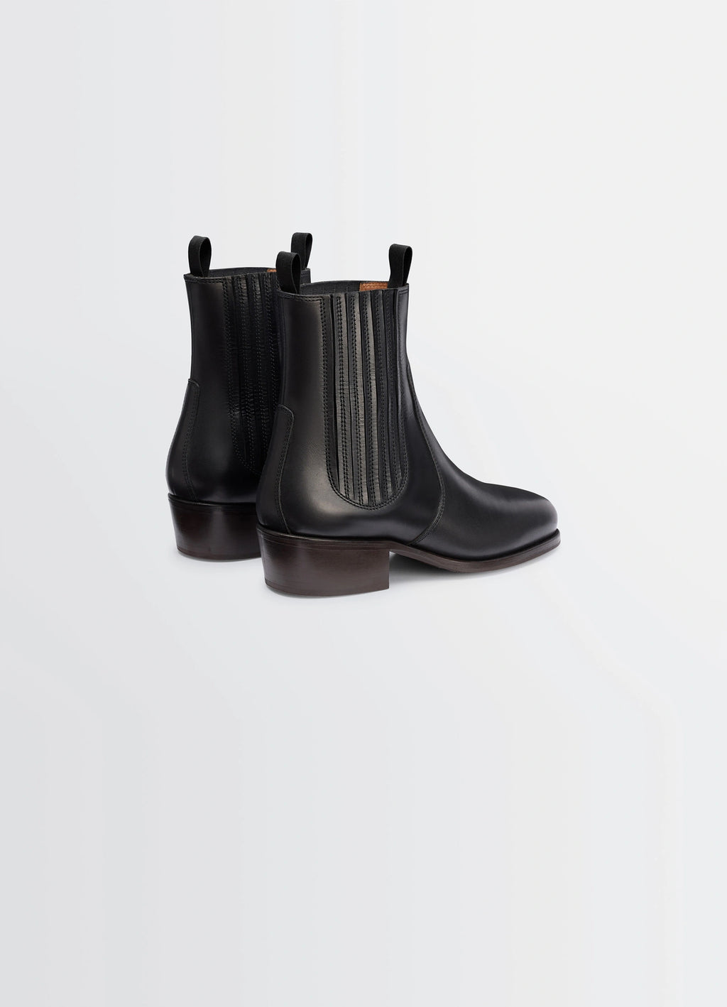 Chelsea boots in black vegetable-tanned leather, product shot, rear three-quarter view stacked heel, sleek finish