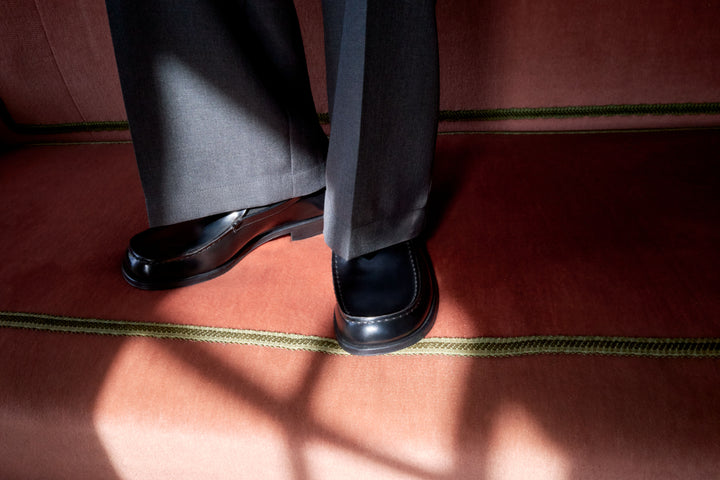 Black leather loafers in Black leather, dark gray fabric, model shot, Worn side view Tailored fit pants