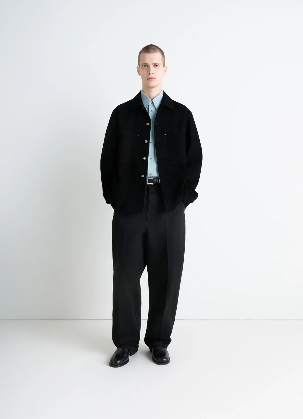 Lemaire workwear overshirt in deep black medium-weight denim, model shot, three-quarter view worn with hands in pockets