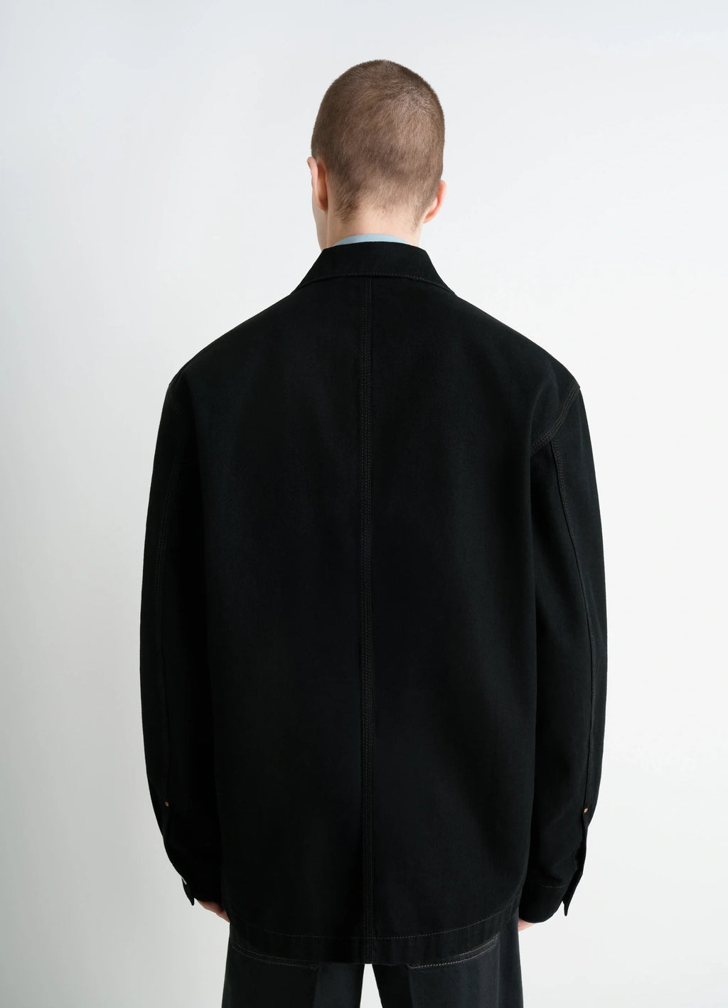Lemaire workwear overshirt in deep black medium-weight denim, model shot, back view loose fit, buttoned cuffs