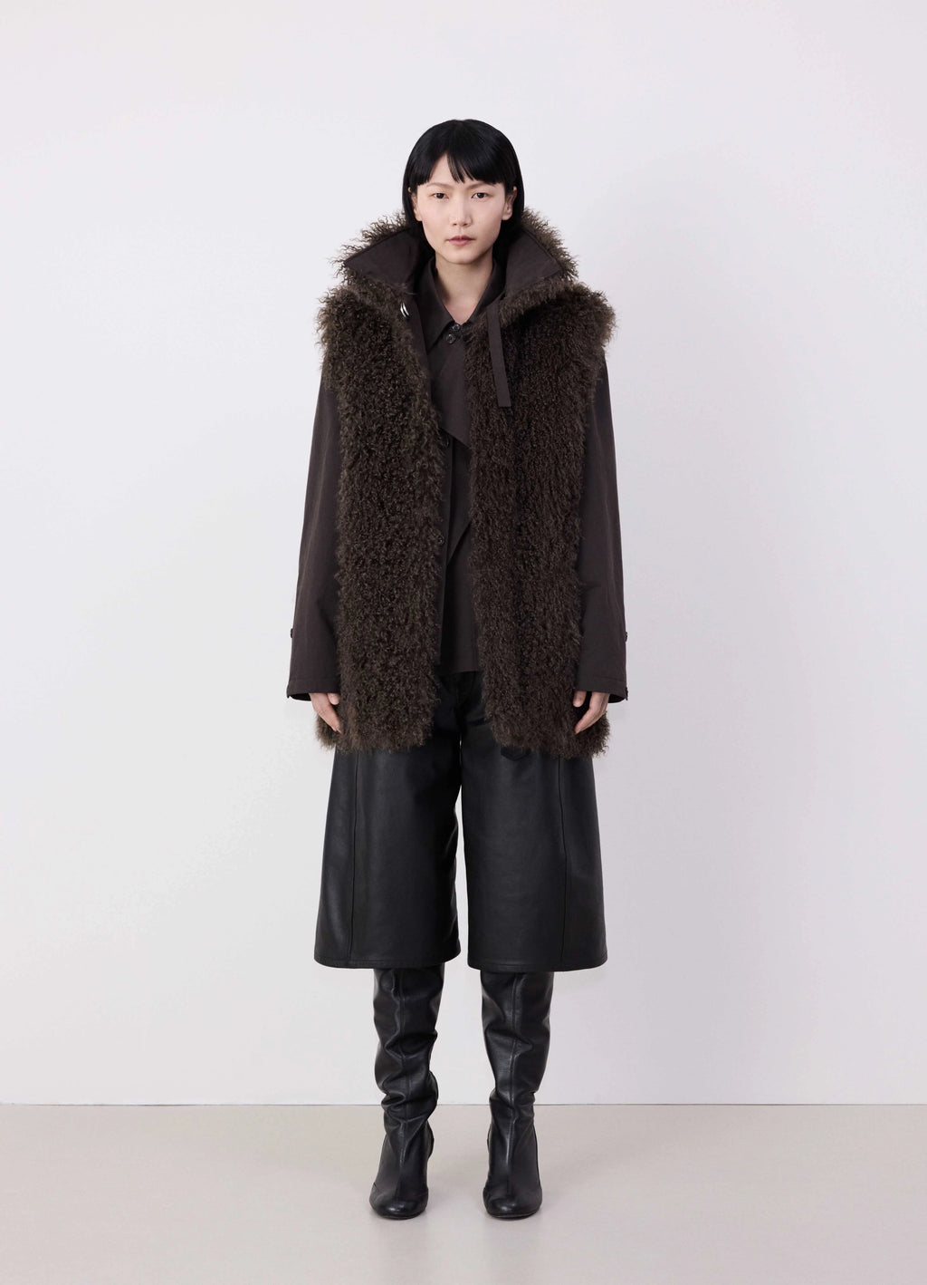 Lemaire reversible belted long shea in dark shearling and cotton twill, model shot, front view with hood full length worn by