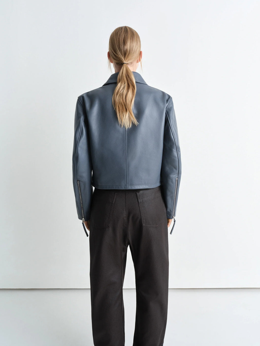Boxy cropped jacket in heavy cow leather, model shot, back view zippered sleeve cuffs