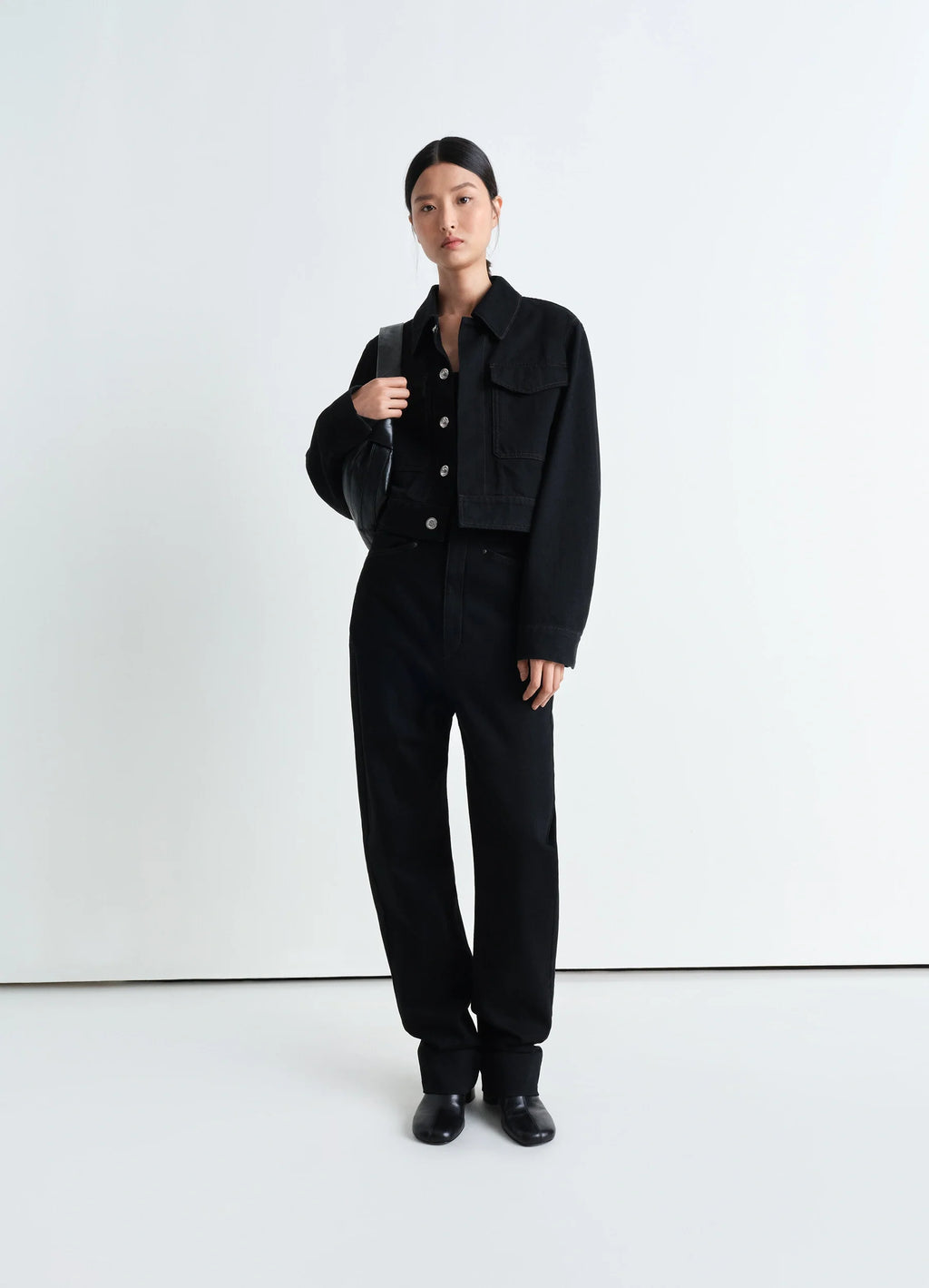 Lemaire two pocket cropped jacket in deep black heavy denim, model shot, three-quarter view structured shoulders