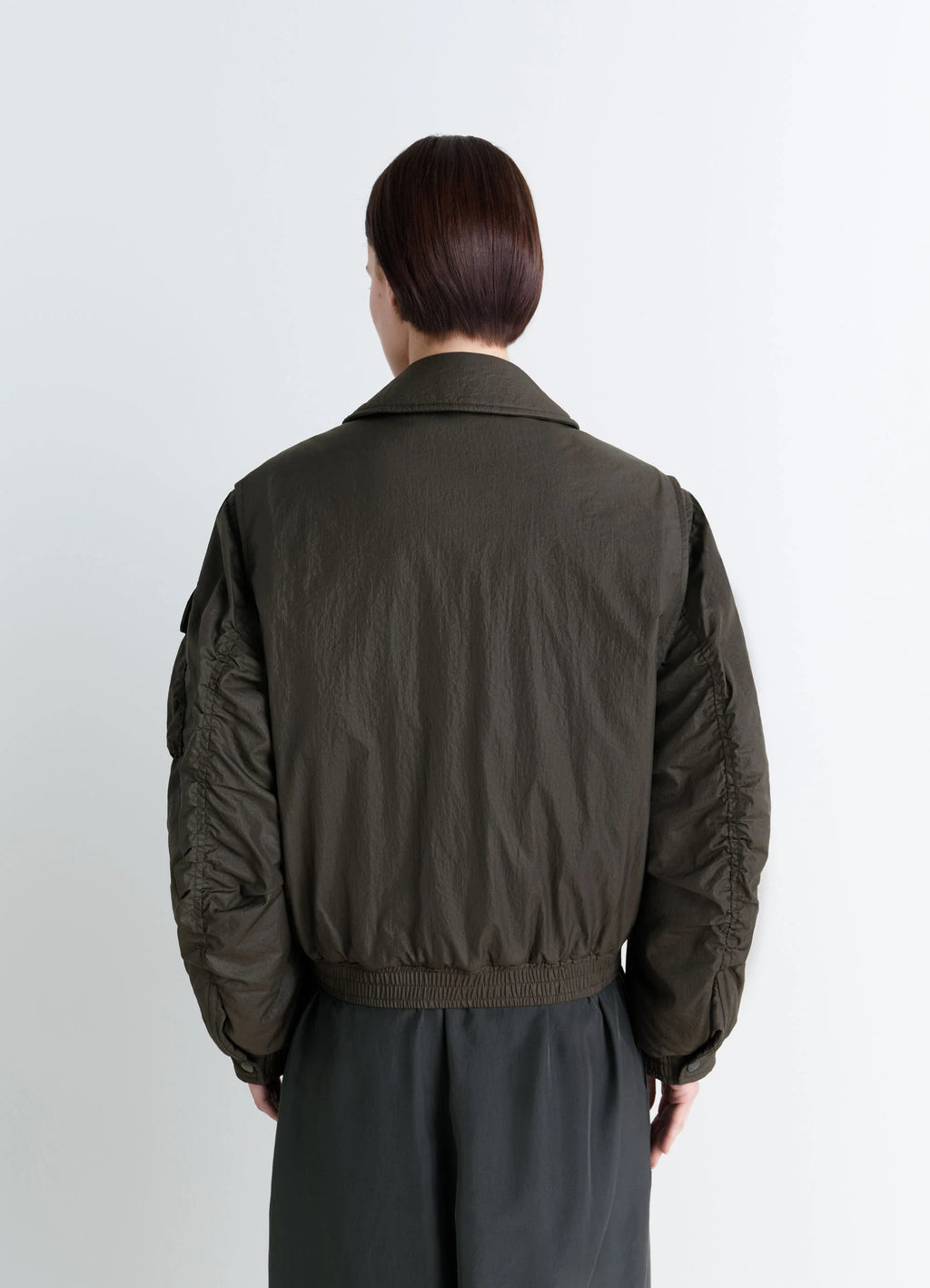 Lemaire short bomber in olive water-repellent nylon, model shot, back view cinched waistband