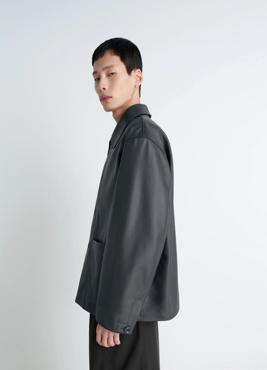 Lemaire leather workwear jacket in thick cow leather, grained, model shot, side view buttoned cuffs, relaxed fit