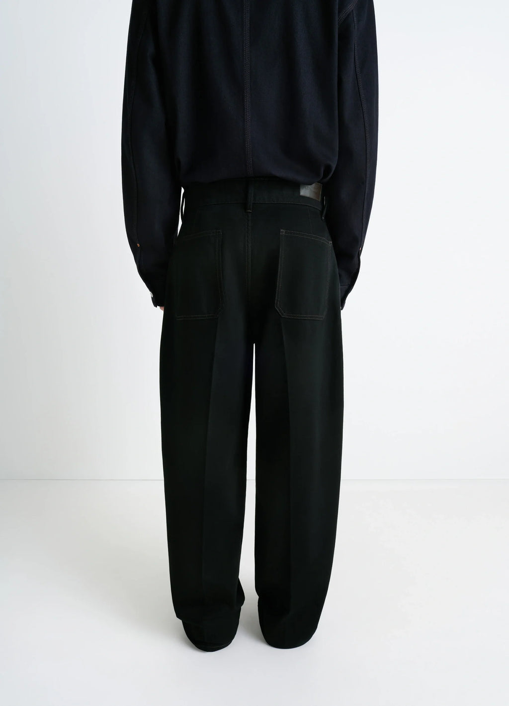 Lemaire maxi barrel workwear pants in deep black thick denim, model shot, back full view straight oversized fit