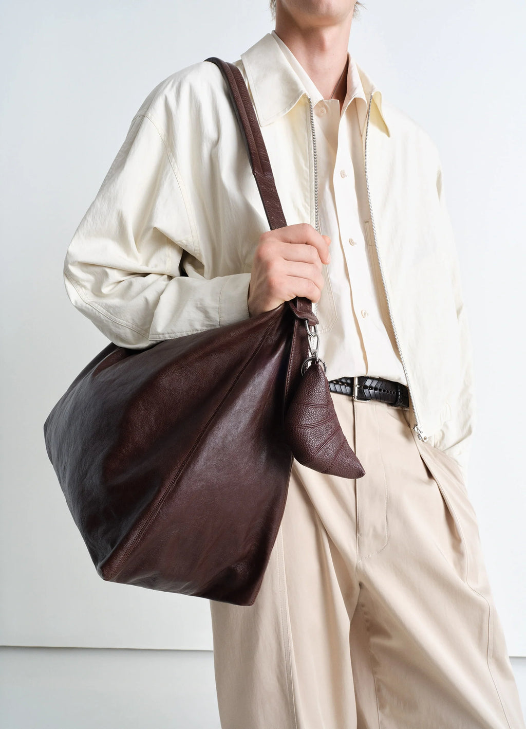 Mini croissant keyring in grained leather, model shot, detail shot hanging on bag