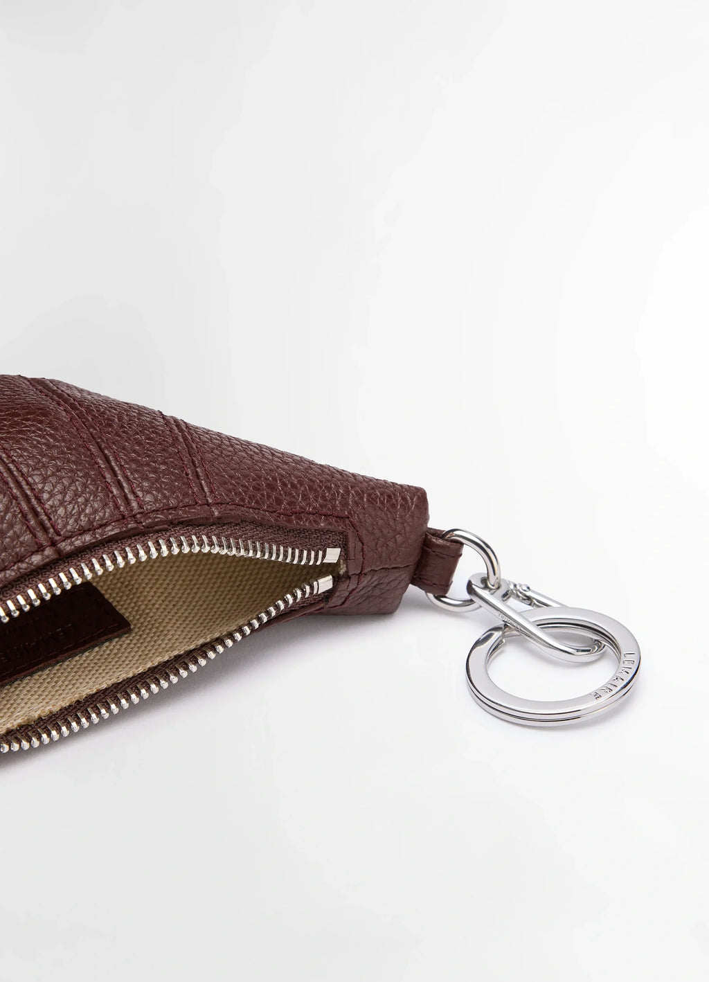 Mini croissant keyring in grained leather, product shot, zipper opening view metal ring detail