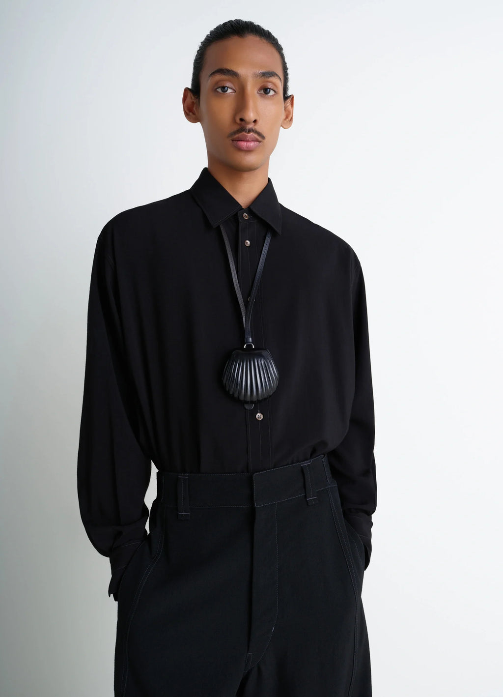 Carlos shell coin purse necklace in black vegetable-tanned leather, model shot, side view worn by model