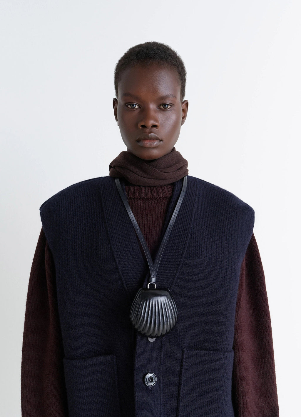 Carlos shell coin purse necklace in black vegetable-tanned leather, model shot, top view over dark sweater