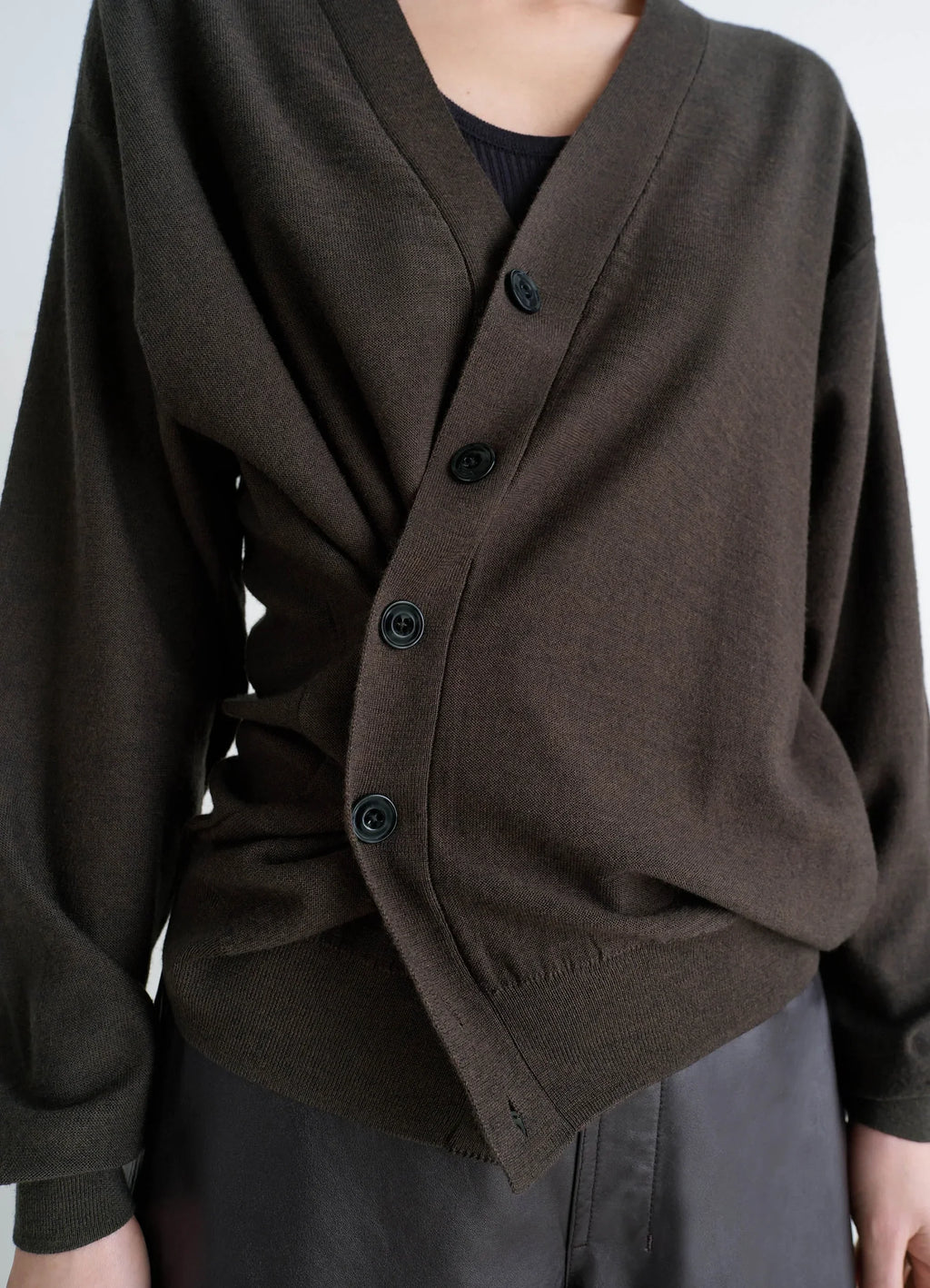 Lemaire relaxed twisted cardigan in knitted merino wool, model shot, close-up side view asymmetrical draped wrap