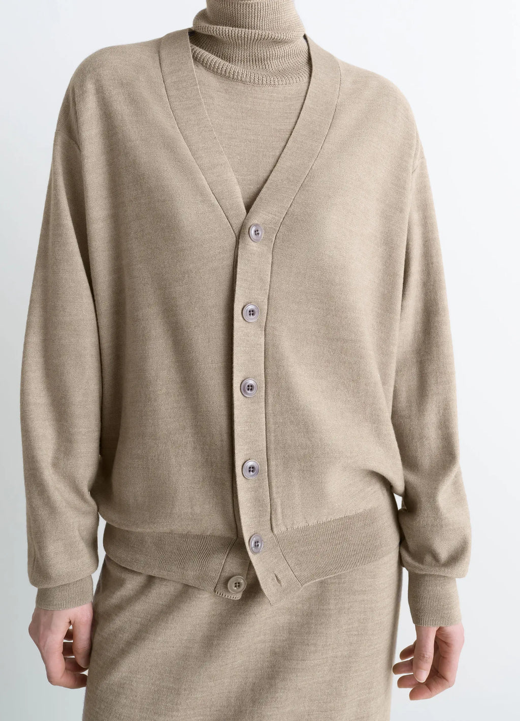 Lemaire relaxed twisted cardigan in light beige blended merino wool, model shot, lower torso close-up button details visible